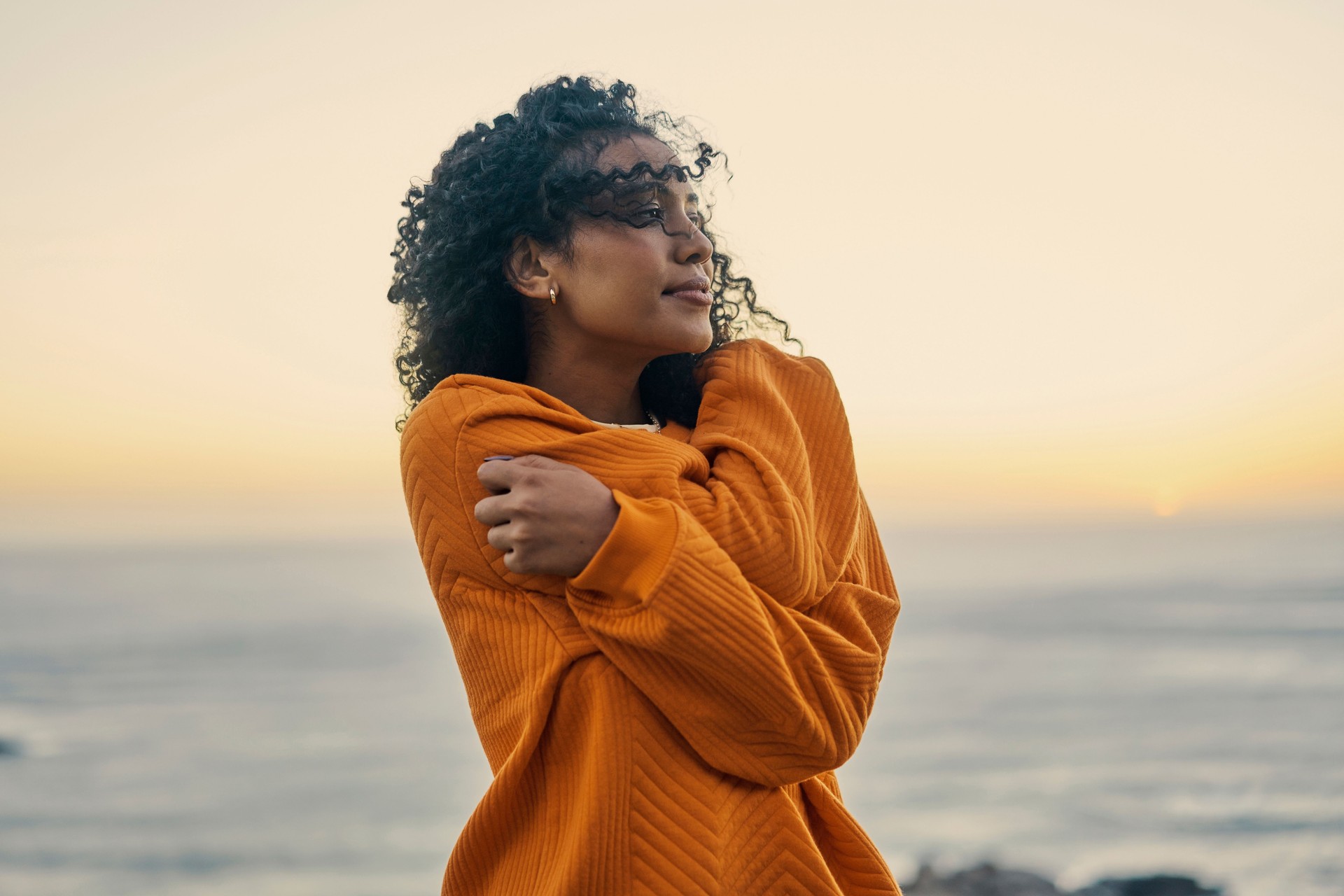 Relax, freedom and self love with a woman at the beach with the sea or ocean and horizon in the background. Water, nature and view with a young female outside and the wind blowing in her hair